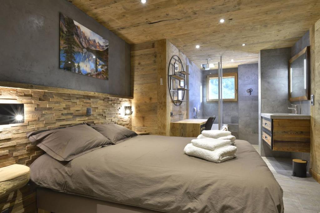 a bedroom with a large bed and a stone wall at La cabane luxury apartment in the heart of the village in La Grave