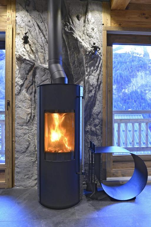 a stove with a fire in a room with a window at La cabane luxury apartment in the heart of the village in La Grave