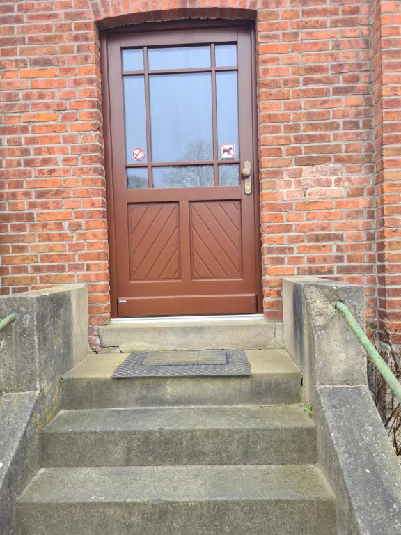 una puerta marrón en un edificio de ladrillo con escaleras en Immergrün en Wustrow