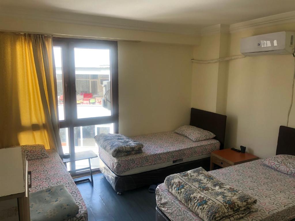 Cette chambre comprend 3 lits et une fenêtre. dans l'établissement DİZLEK PANSİYON, à Antalya