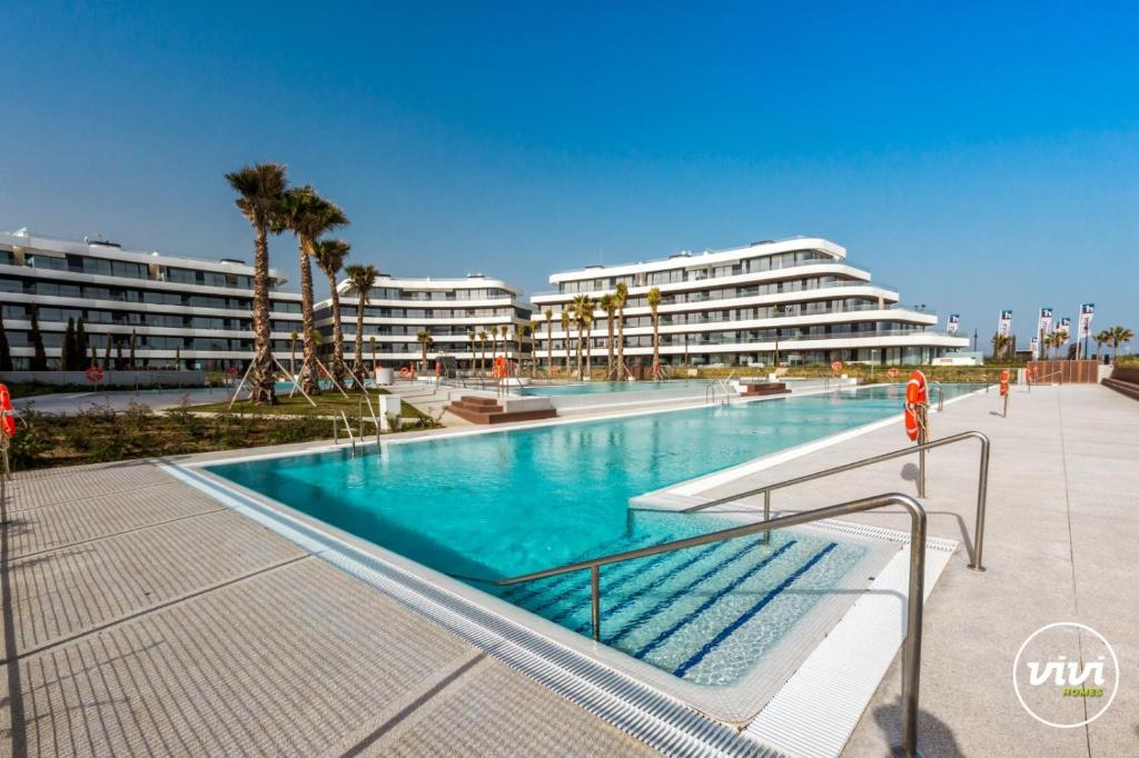 einen Pool in einem Resort mit Palmen und Gebäuden in der Unterkunft ViVi Homes - Galatea Pool, Gym, Sauna & Beach in Torremolinos