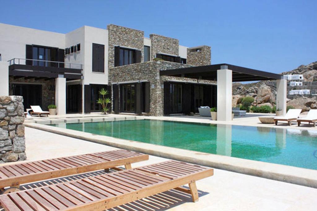 a house with a swimming pool in front of it at Endorikles Villa in Super Paradise Beach