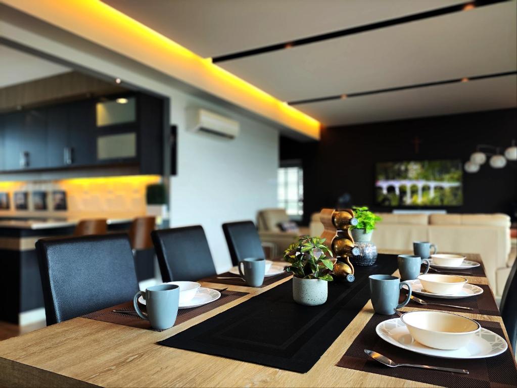 a long wooden table with plates and cups and plants on it at Bright Cozy 3 Bedrooms in Sibu