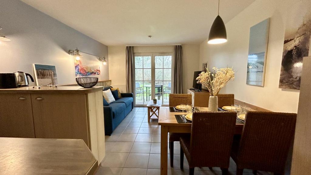 a kitchen and living room with a table and a blue couch at Argousiers 21 in Fort-Mahon-Plage
