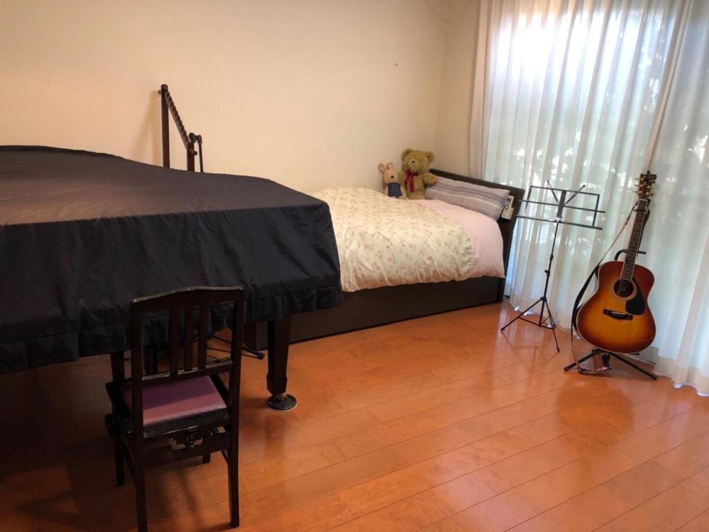 um quarto com uma cama com uma guitarra e uma cadeira em KOTO TEA HOUSE - Vacation STAY 12837 em Kumamoto
