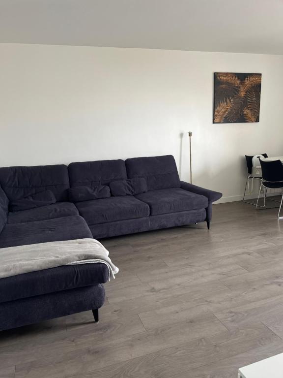 - un canapé noir dans le salon doté de parquet dans l'établissement La Rose, à Drancy