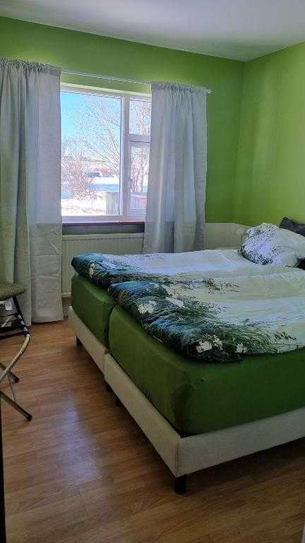 a green bedroom with a bed with a window at Fornilækur Guesthouse in Blönduós