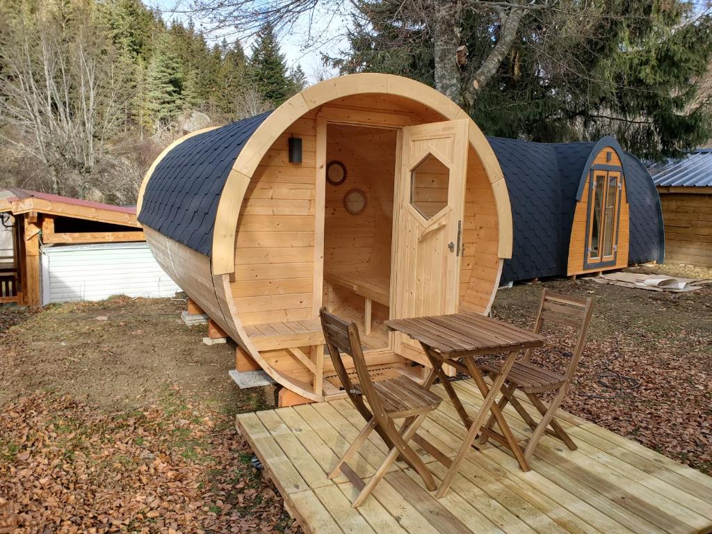 Cette maison en bois comprend une table et deux chaises. dans l'établissement camping hôtel les airelles, à Saint-Cirgues-en-Montagne