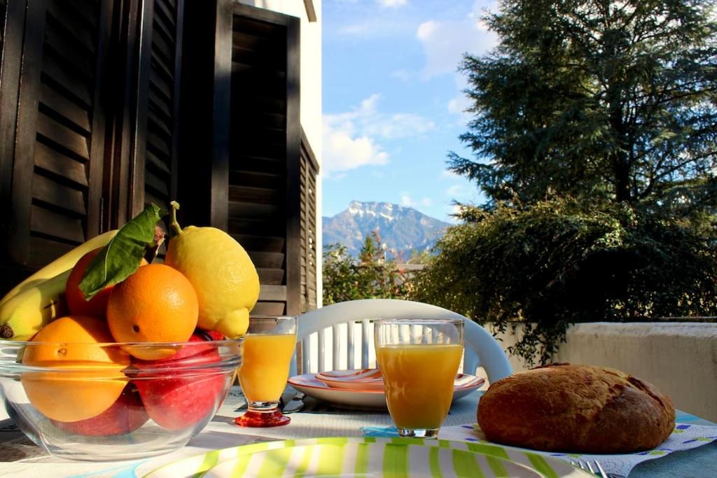 a table with a bowl of fruit and orange juice at [Fronte lago]ResidenceGarden, moderno appartamento in Calceranica al Lago