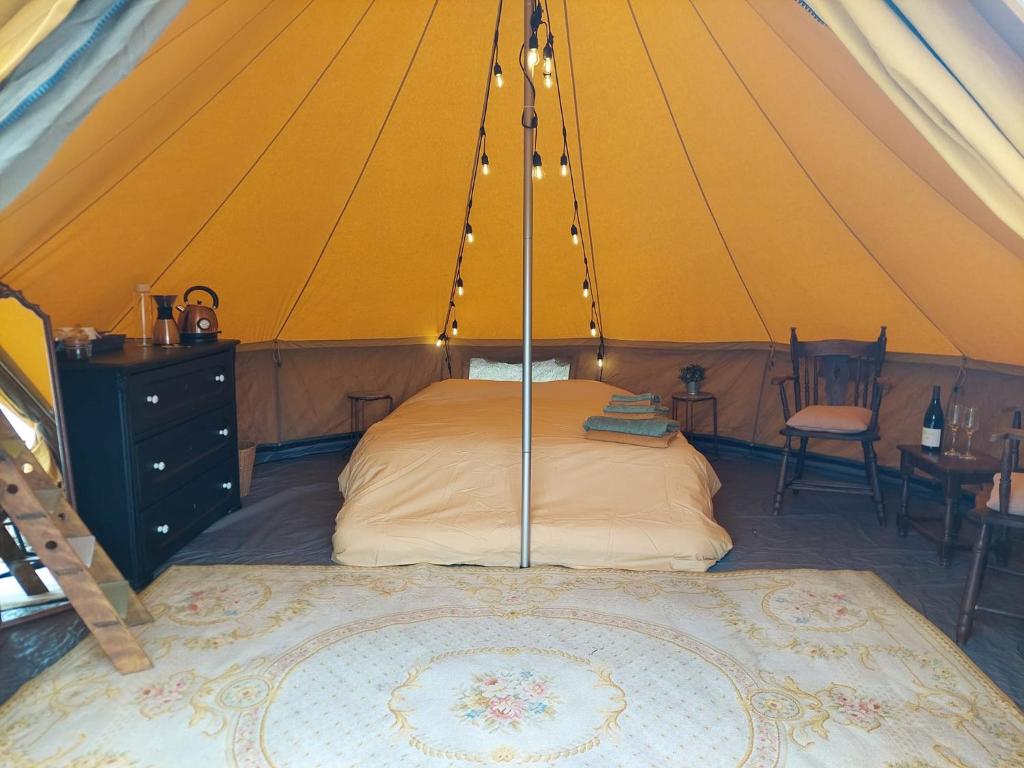 um quarto numa tenda com uma cama e uma mesa em Glamping Hoeve Thenaers em Gingelom