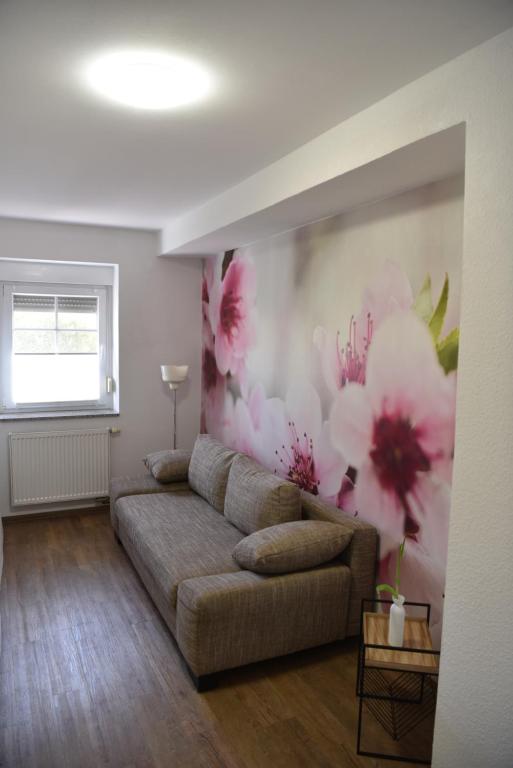 a living room with a couch and flowers on the wall at Ferienwohnung am Netzener See in Lehnin