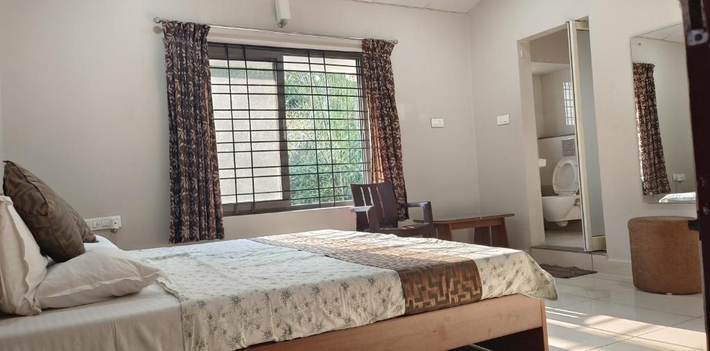 a bedroom with a bed and a large window at Sugamya Farm Guesthouse in Sāgar