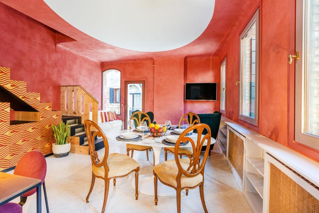 a dining room with red walls and a table and chairs at Appartamento di lusso con terrazza sull'acqua in Venice