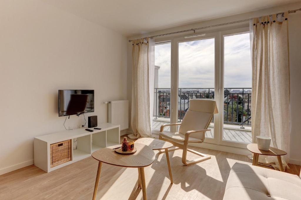 uma sala de estar com televisão e uma grande janela em Le Pasteur - LeBlanc Mesnil em Le Blanc-Mesnil