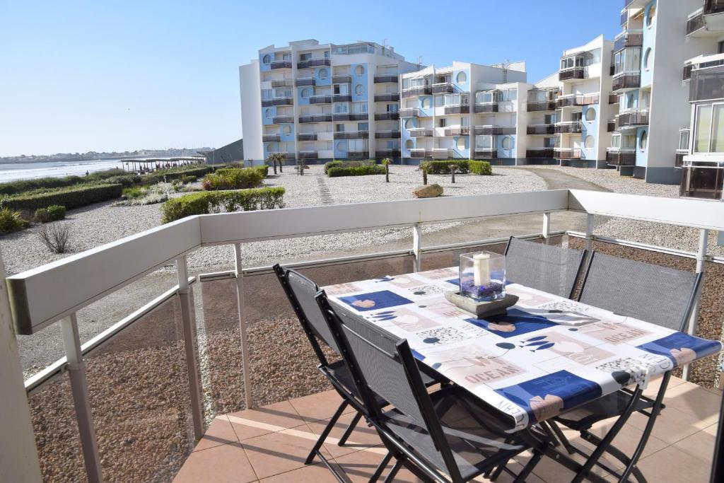 une table et des chaises sur un balcon avec vue sur la plage dans l'établissement L'Escadrille, à Saint-Gilles-Croix-de-Vie