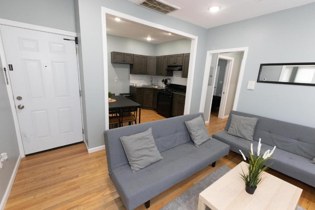 a living room with a blue couch and a kitchen at Mins to NYC - Stylish 3 Bedroom Haven in Jersey City