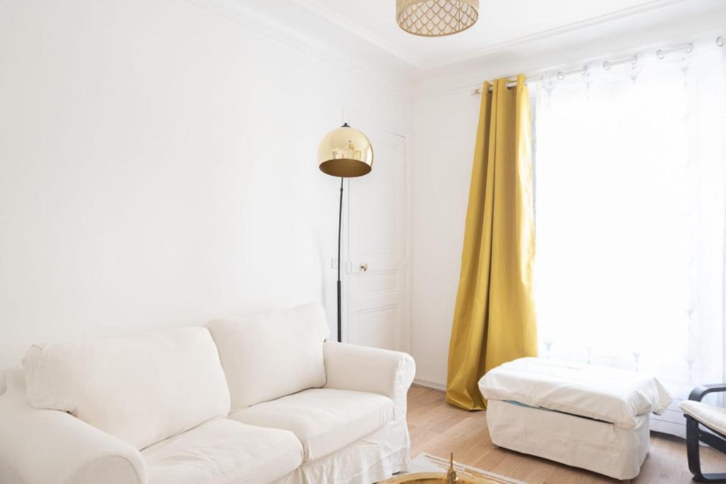 - un salon avec un canapé blanc et des rideaux jaunes dans l'établissement Apt near Montmartre and Pigalle, à Paris