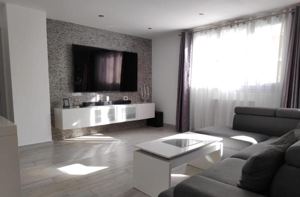 un salon avec un canapé et une télévision sur un mur dans l'établissement Appartement moderne à Uzès, 70 m², proche centre-ville, à Uzès