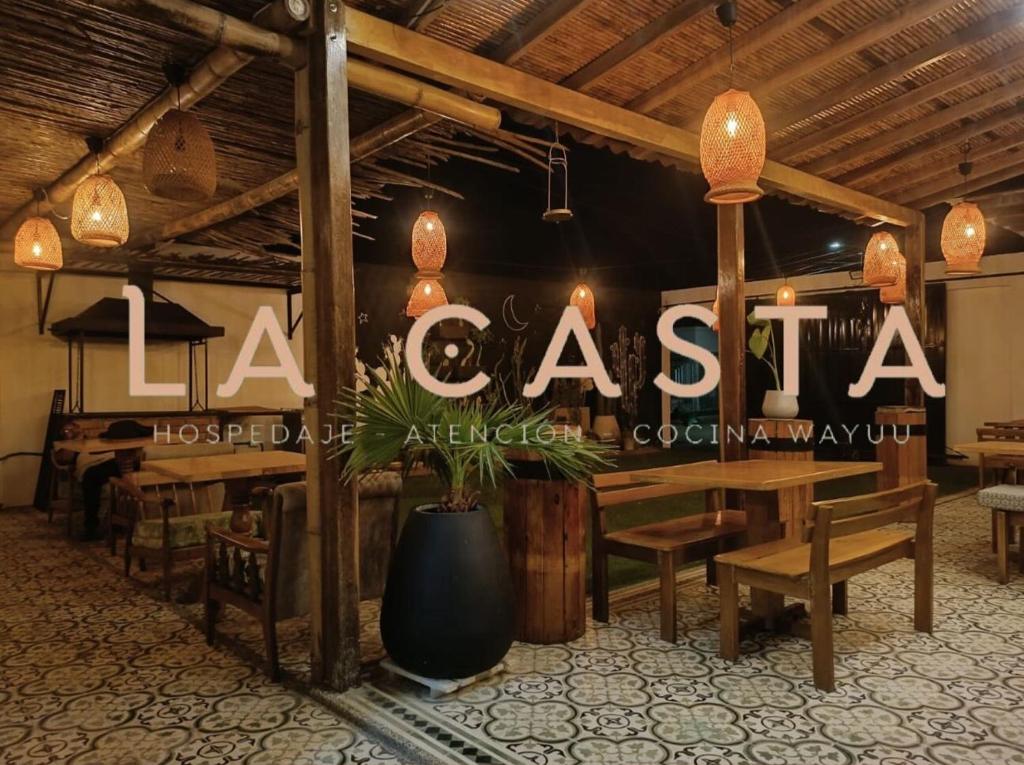 un restaurante con mesas de madera y un cartel que lee la casita en Hostal La Casta en Camarones