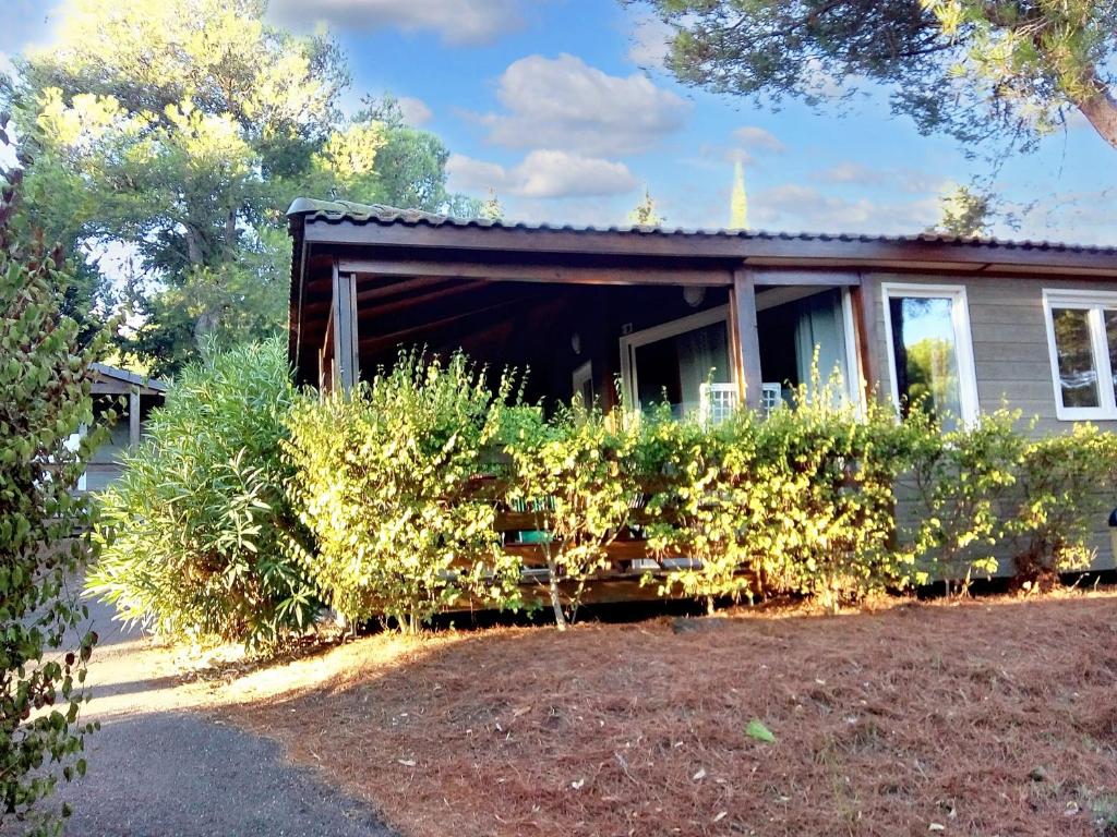 une maison avec des buissons devant elle dans l'établissement Bungalow paisible à Agde avec piscine partagée, à Agde