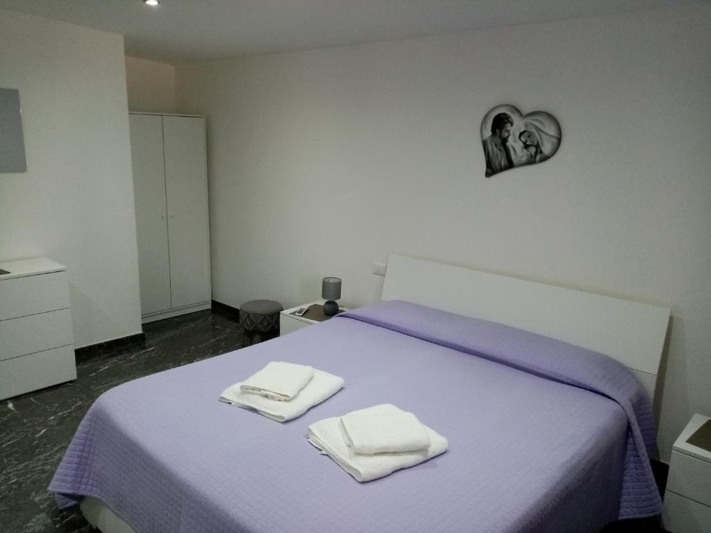 1 dormitorio con 1 cama morada y 2 toallas en Cofano Home, en Custonaci