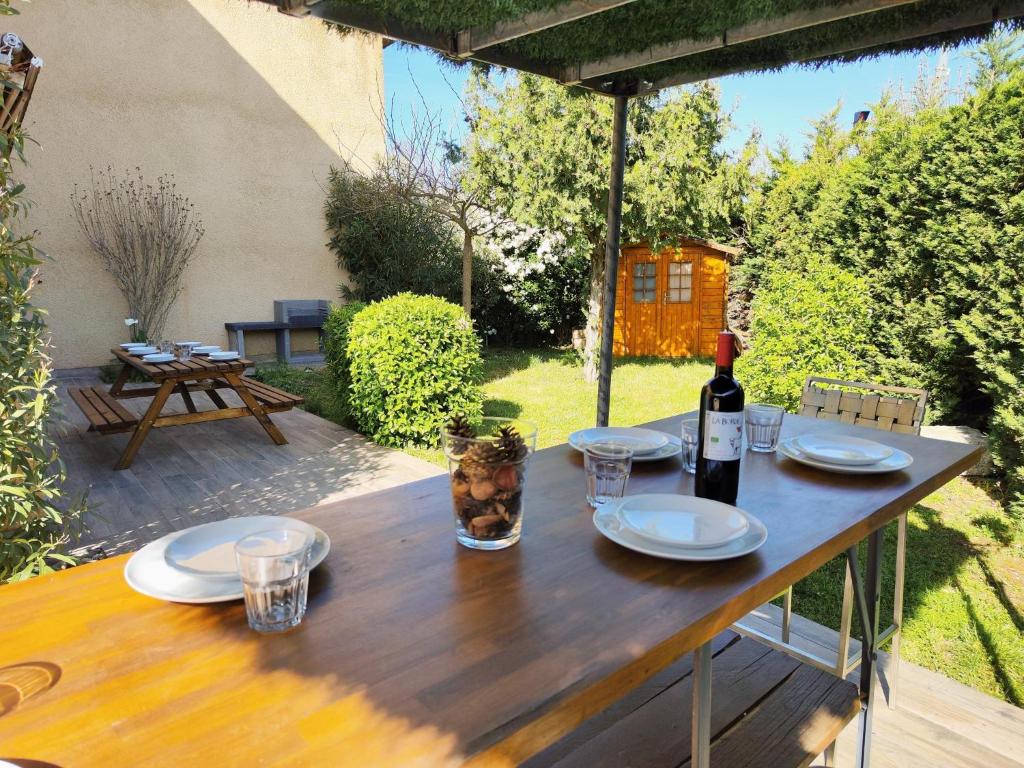 - une table en bois avec une bouteille de vin dans l'établissement Le PATIO GARONNE maison 6 personnes, climatisé, Netflix, à Portet-sur-Garonne