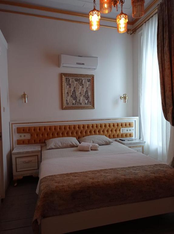 - une chambre avec un grand lit et une tête de lit en bois dans l'établissement BUDAKZADE KONAĞI OTEL-RESTAURANT 1841, à Karşıyaka