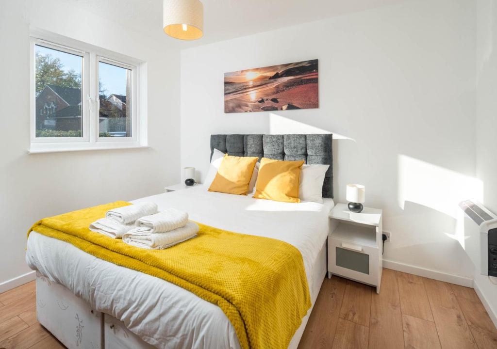 a white bedroom with a large bed with yellow sheets at Crawley Maunsell Park Charm & Cosy 1 Bedroom Apartment with Parking in Crawley