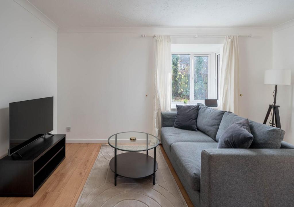 a living room with a gray couch and a glass table at Crawley Maunsell Park Charm & Cosy 1 Bedroom Apartment with Parking in Crawley