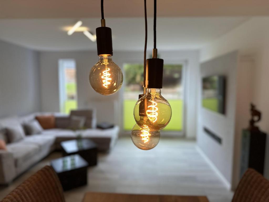 3 Lichter hängen in einem Wohnzimmer mit Sofa in der Unterkunft VennOase in Monschau