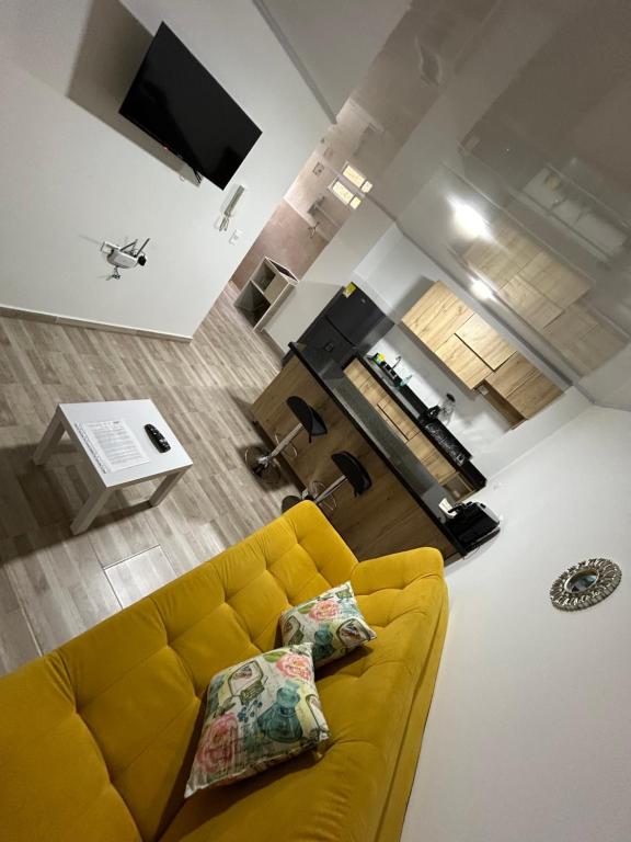 a living room with a yellow couch and a kitchen at AMARU Apartamentos San Gil in San Gil