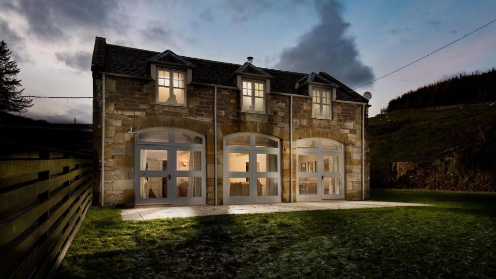 a large brick house with white garage doors at The Coach House, Pentland Hills in Nine Mile Burn