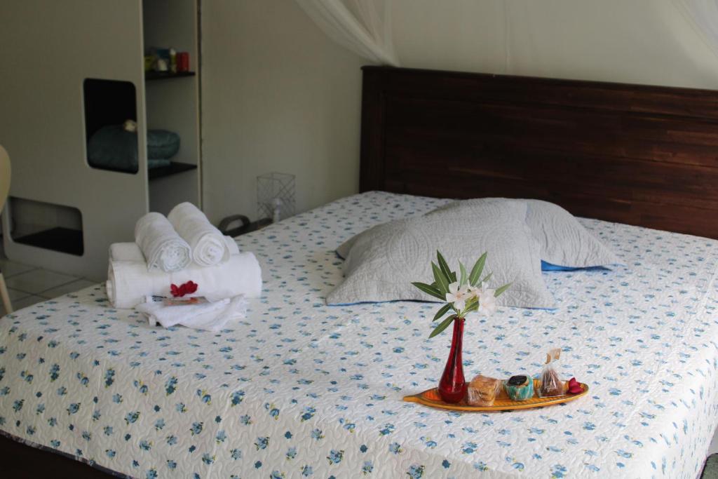 a bed with a tray with towels and a plate with a flower at Le Colibri et le Frangipanier in La Trinité