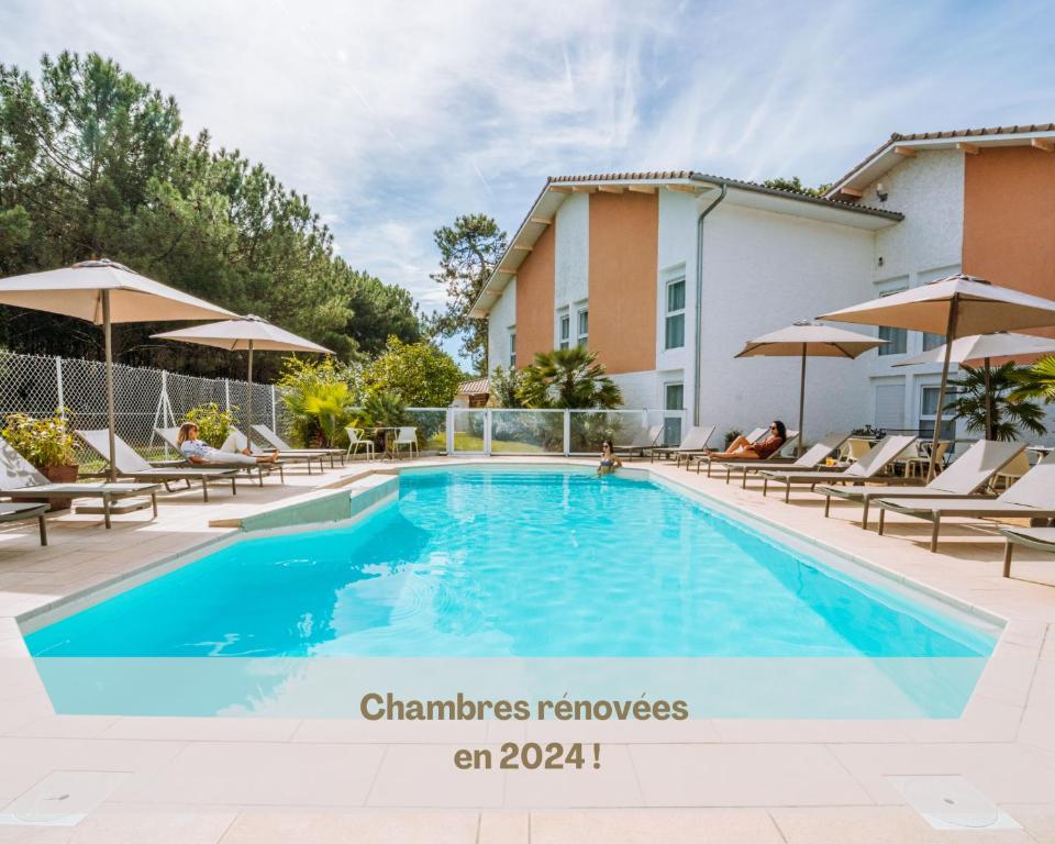 a swimming pool at a hotel with chairs and umbrellas at Hôtel Restaurant La Forestière in Biscarrosse-Plage