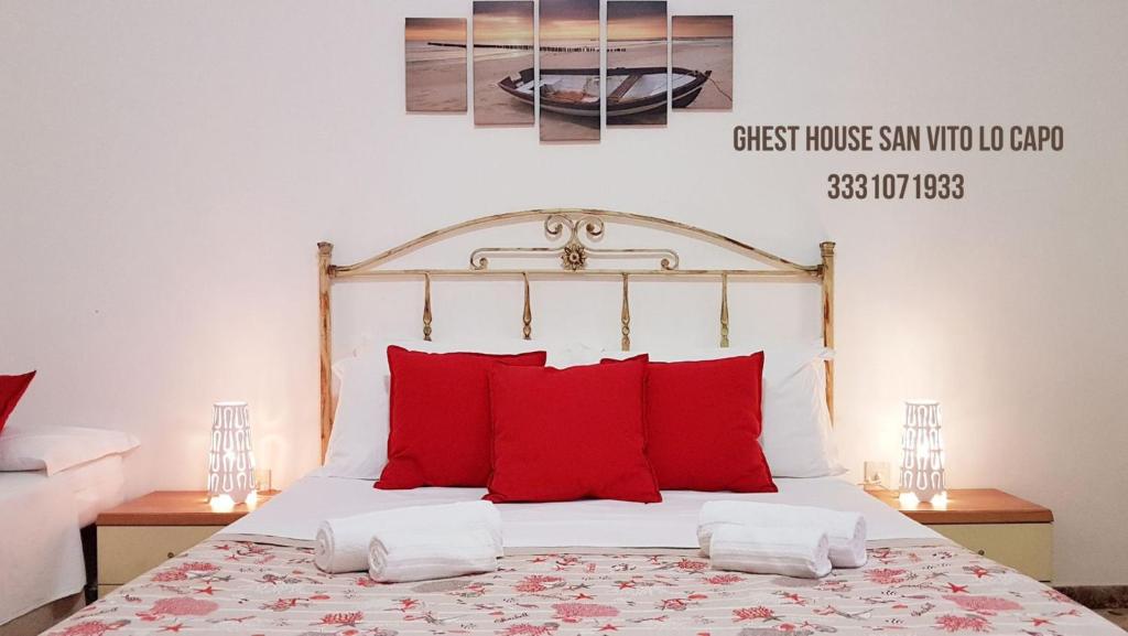 una camera da letto con un grande letto con cuscini rossi di Guest House San Vito Lo Capo a San Vito lo Capo