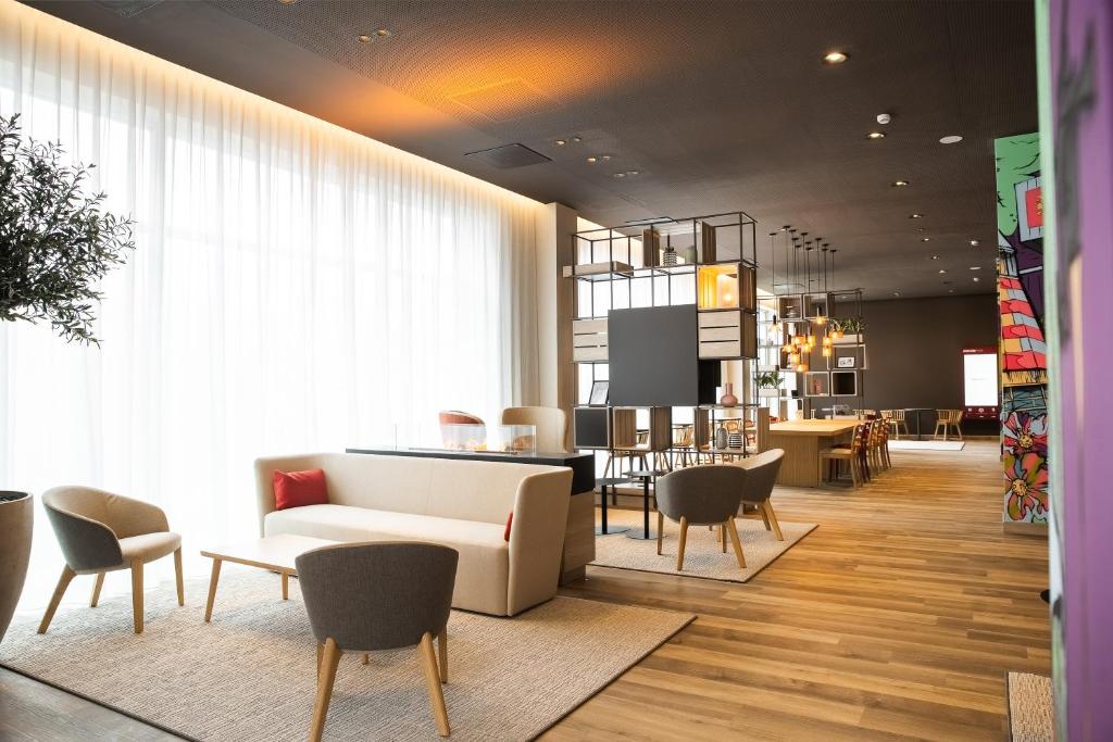 a living room with a white couch and chairs at IntercityHotel Breda in Breda
