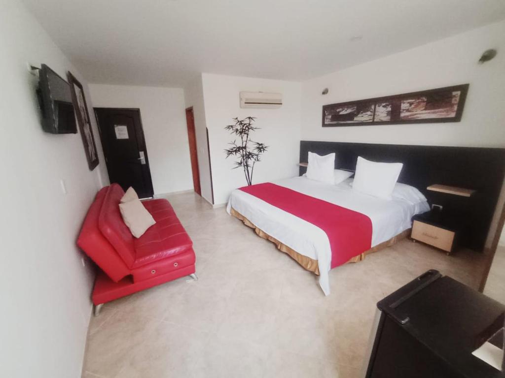 a bedroom with a large bed and a red chair at Hotel Alessio in Bucaramanga