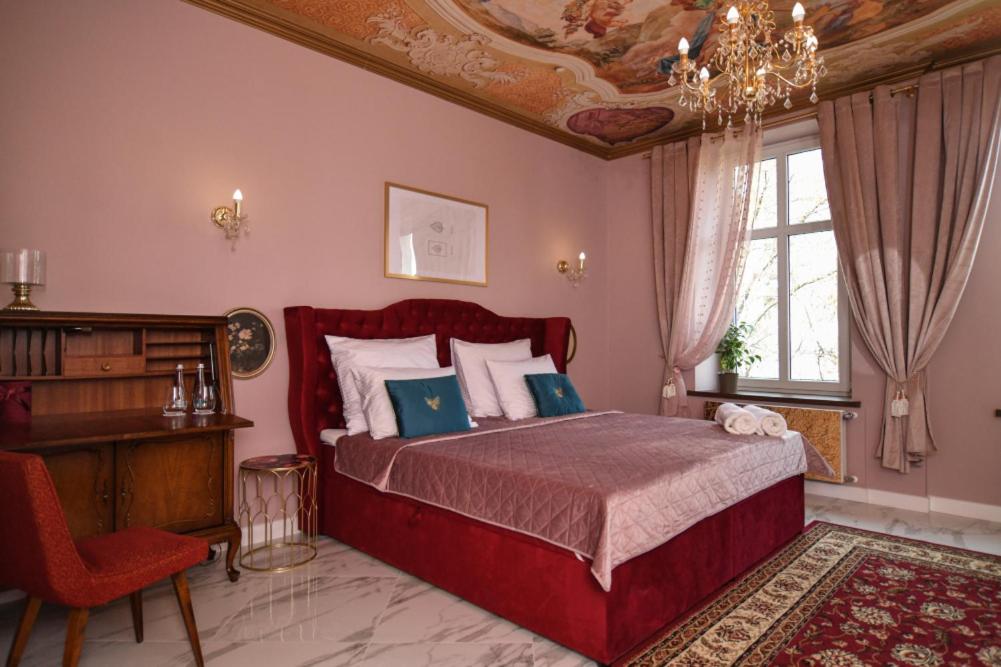 um quarto com uma grande cama vermelha e uma secretária em Apartament Książęcy przy Zamkowej w Wałbrzychu em Wałbrzych