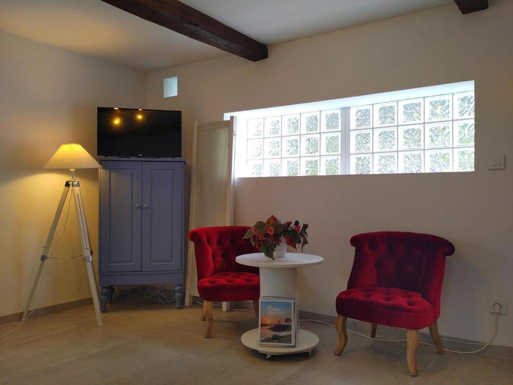 een kamer met 2 rode stoelen, een tafel en een raam bij Détour en baie de somme in Le Crotoy