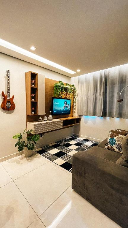 een woonkamer met een bank en een tv bij Stúdio Moderno Cama de Massagem! in Uberlândia