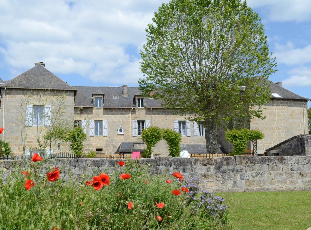 une maison avec un champ de fleurs devant elle dans l'établissement Les Dépendances du Château, à Noailles