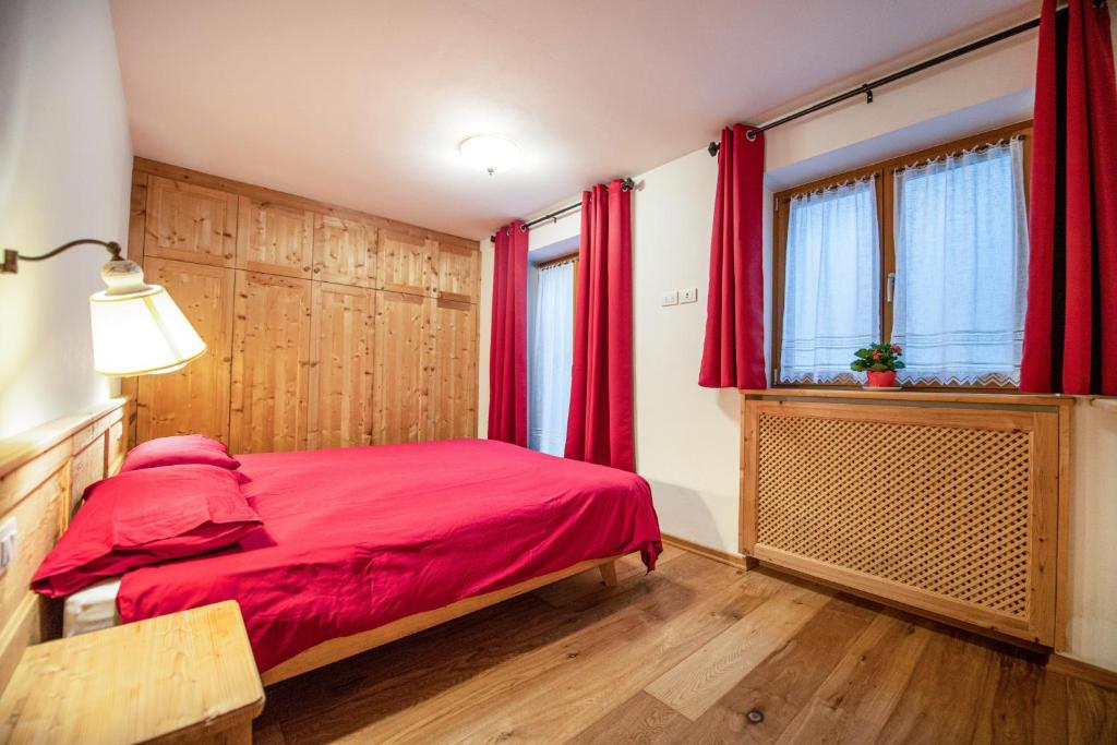 una camera con letto rosso e finestra di Cristina Hospitality a Ortisei