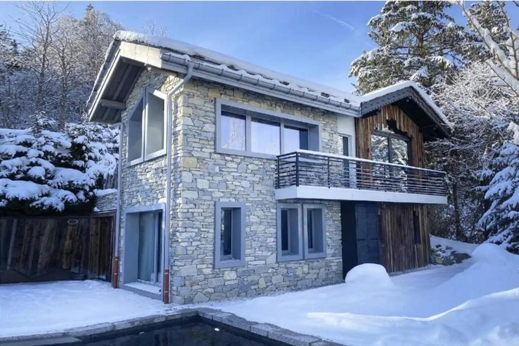 uma casa de pedra com uma varanda na neve em Chalet Ilulissat em Courchevel