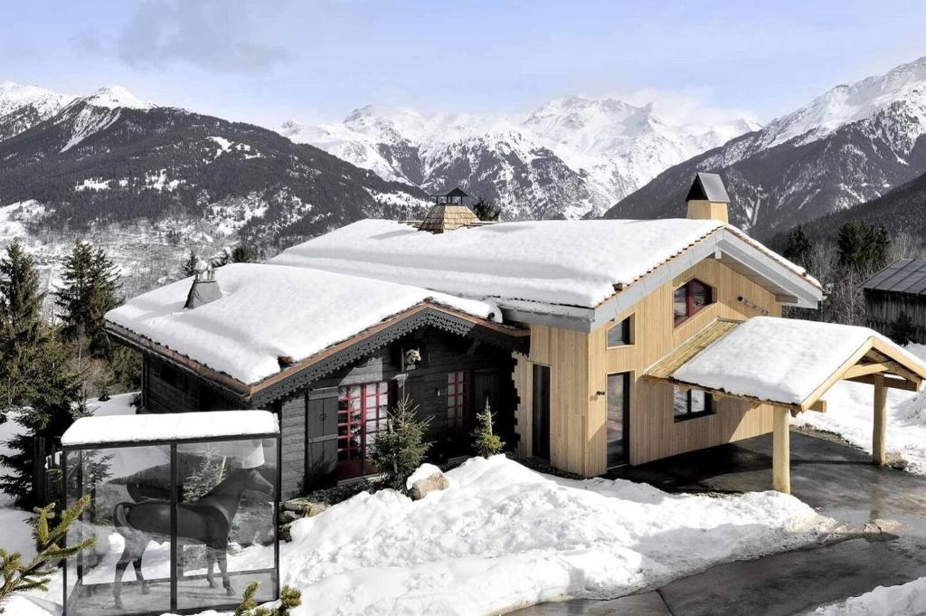 uma casa coberta de neve com montanhas ao fundo em Chalet sisimut em Courchevel