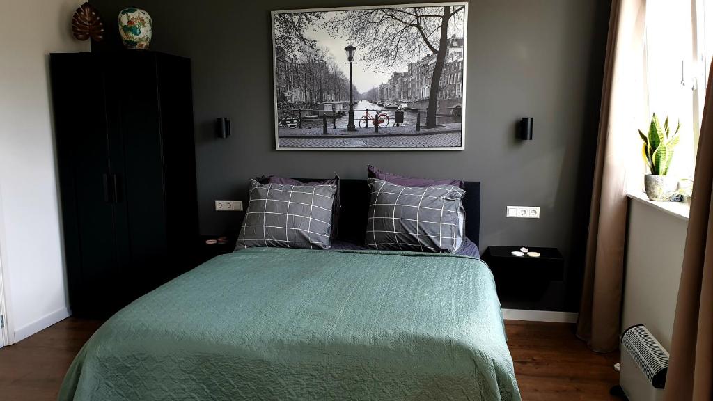 a bedroom with a bed with a green comforter at Amor Guesthouse in Amsterdam