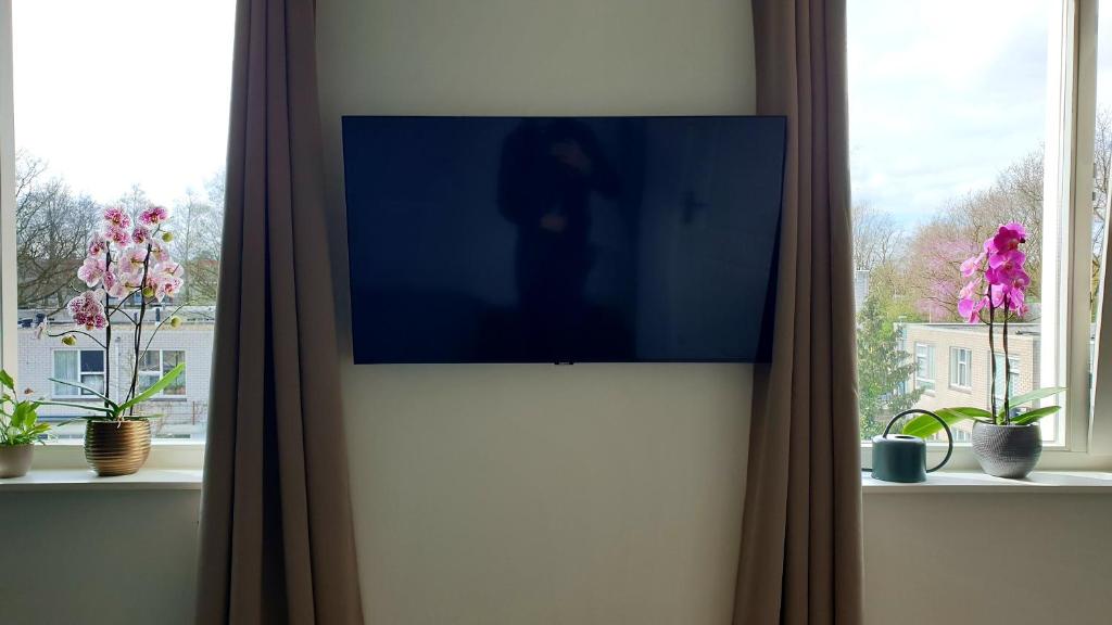 einen TV an der Wand in einem Zimmer mit Fenstern in der Unterkunft Amor Guesthouse in Amsterdam