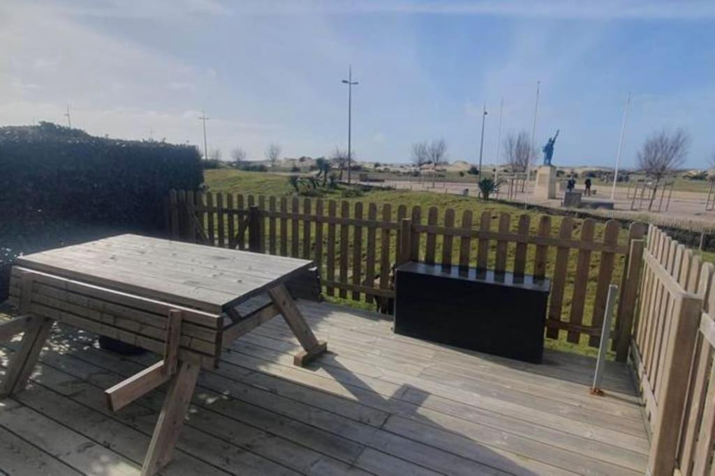 una terraza de madera con una mesa de picnic y una valla en Appartement front de mer - 6198, en Soulac-sur-Mer