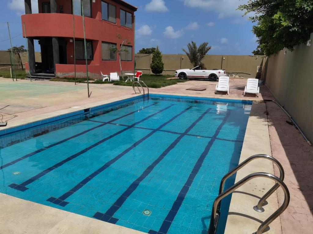 una piscina frente a un edificio en Villa Mostafa Sadek, Swimming pool, Tennis & Squash - Borg ElArab Airport Alexandria, en Borg El Arab