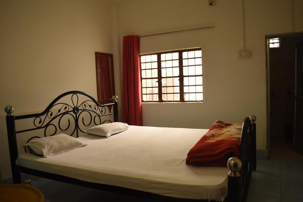 een slaapkamer met een bed met witte lakens en een raam bij Dooars Nest Resort Rahutbari in Chālsa Mahābāri