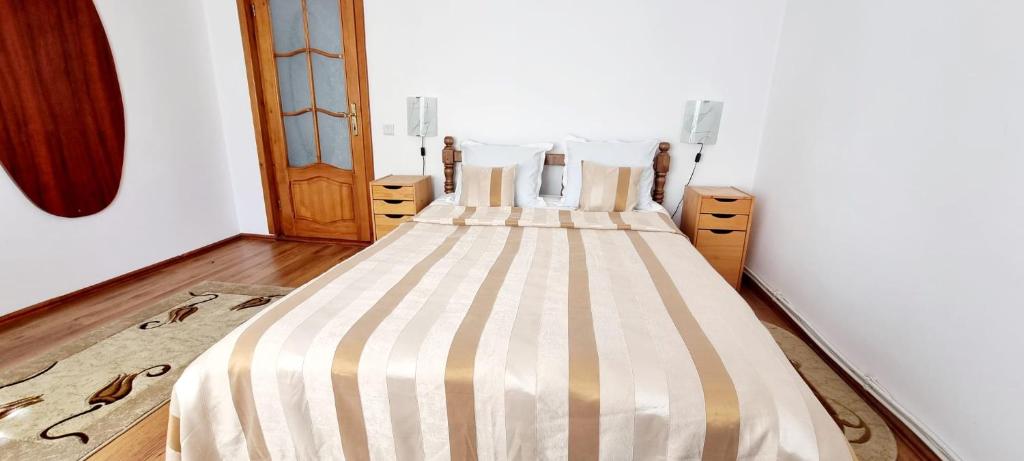een slaapkamer met een bed met een gestreept dekbed bij Pensiunea Miana in Gîrcina de Jos
